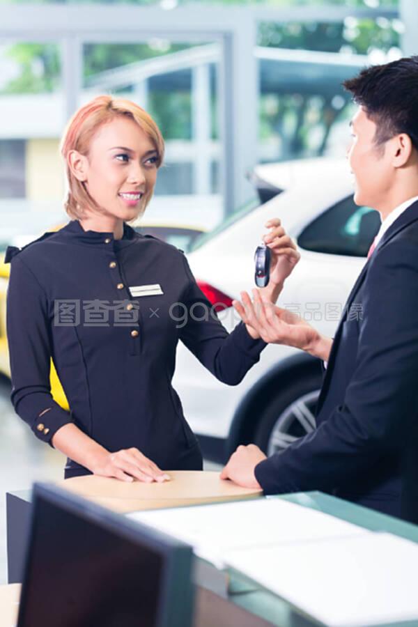 汽车租赁公司的亚洲男子接受钥匙